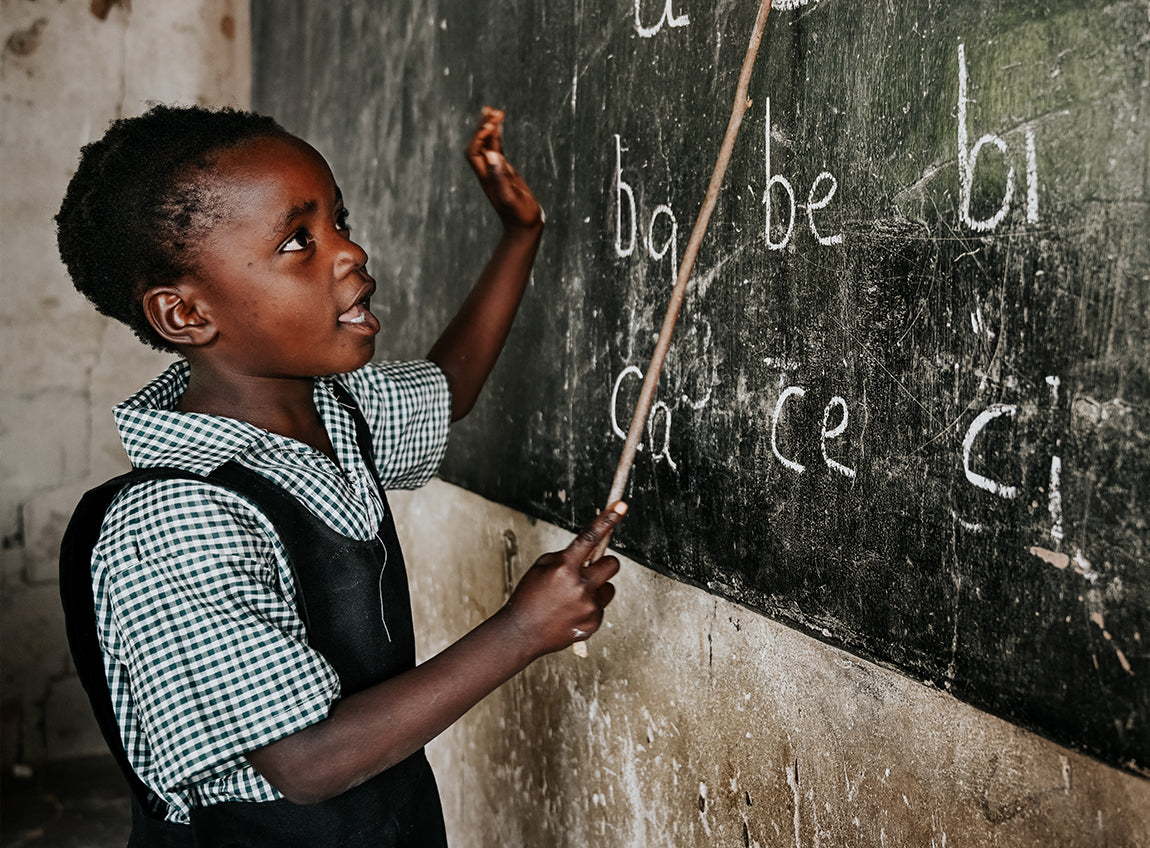 一名女童在課室內指著黑板上的英文字母。