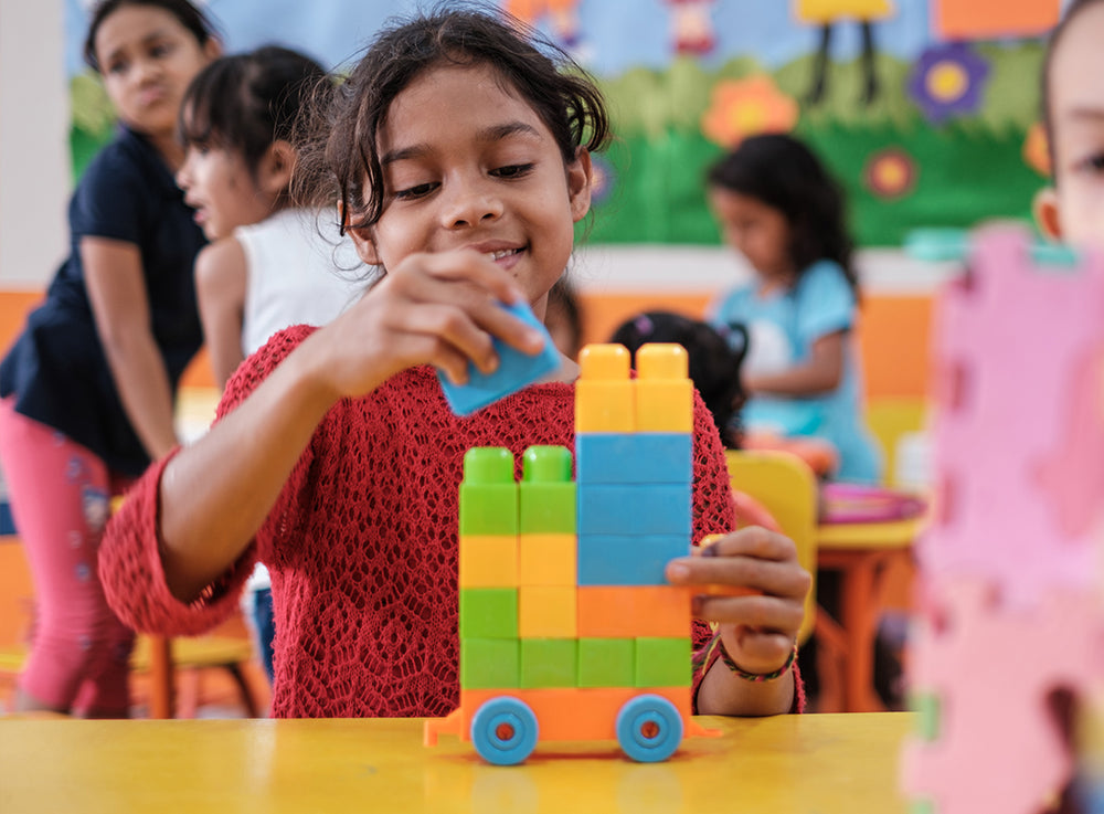 一名女童在課室內疊起色彩繽紛的積木。