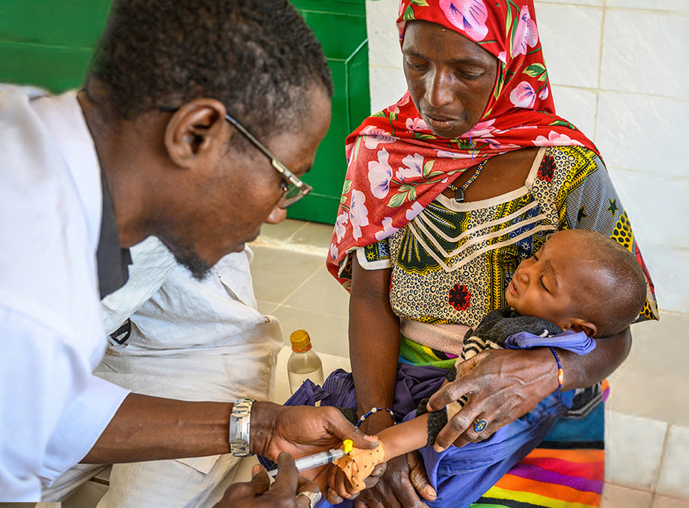一名女士懷裡抱著嬰兒，讓醫生為孩子注射疫苗。