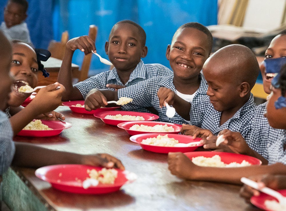 一班學童一邊吃午餐，一邊對著鏡頭微笑。