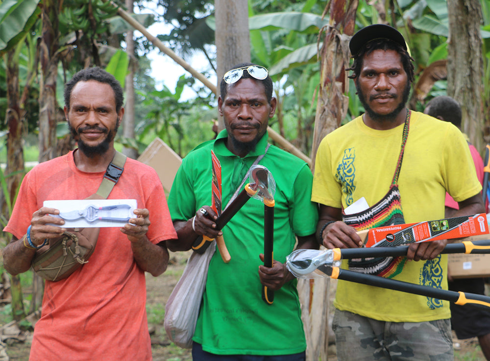 三位男士站在森林內，手裡拿著各種園藝工具。