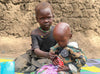 兩個非常年幼的孩童坐在地上，因飢餓而愁容滿面。