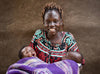 一名婦女向著鏡頭微笑，手裡抱著兩名用紫色毛巾包裹著的嬰兒。